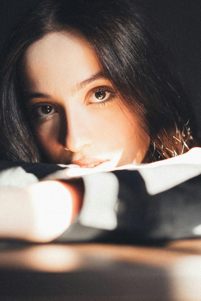 Close-up portrait of a woman with long dark hair and captivating eyes, bathed in natural light.